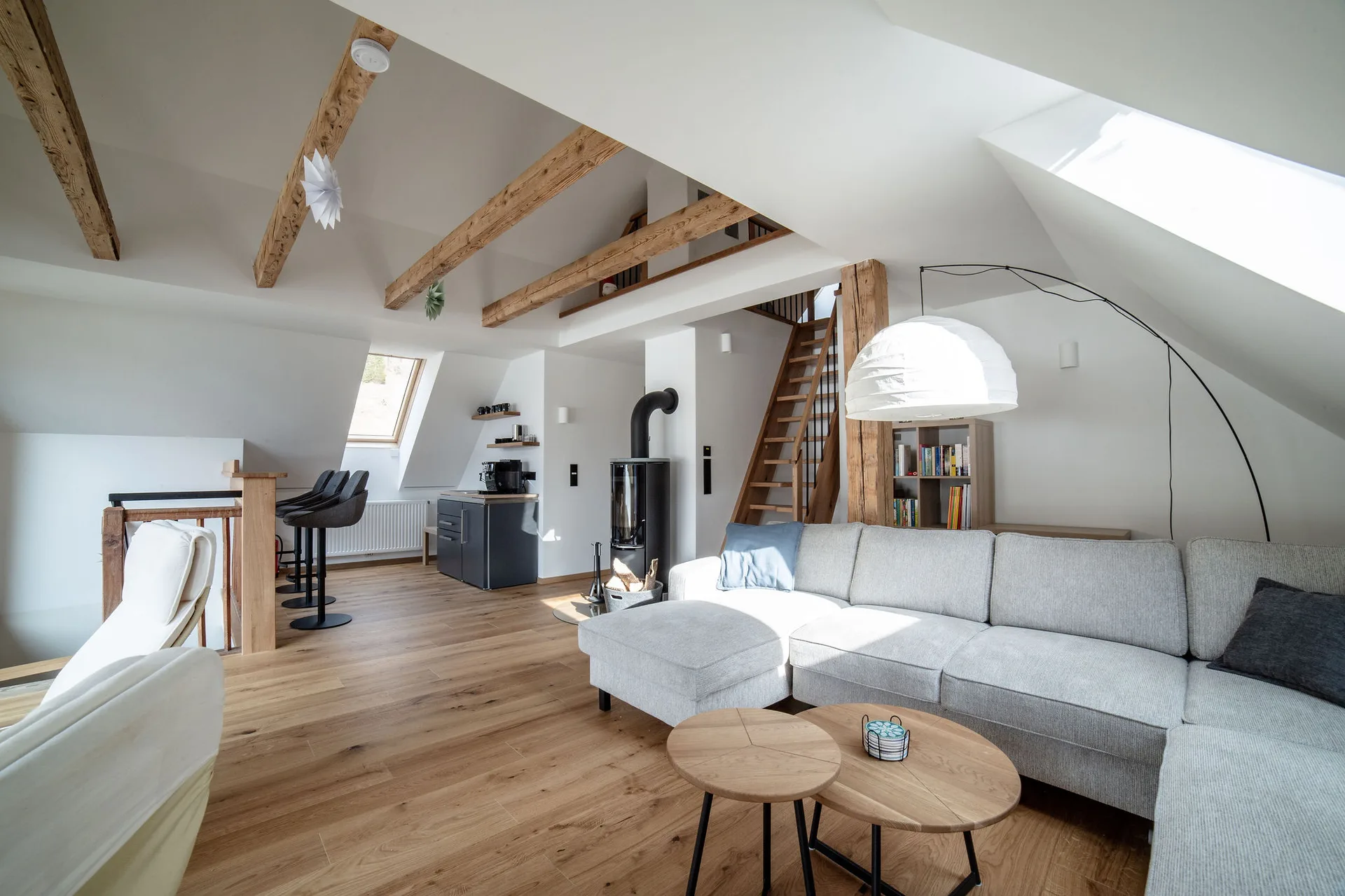 Wohnzimmer im Dachgeschoss mit Kaminofen, Teeküche und Panoramafenster mit Bergblick.